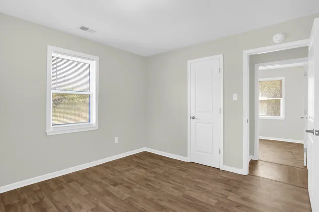 a view of an empty room with wooden floor and a window