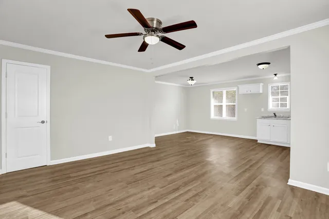 an empty room with wooden floor fan and windows