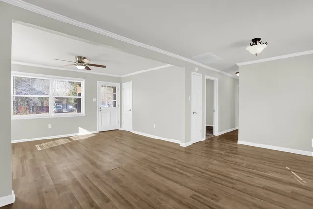 a view of an empty room with a window and wooden floor