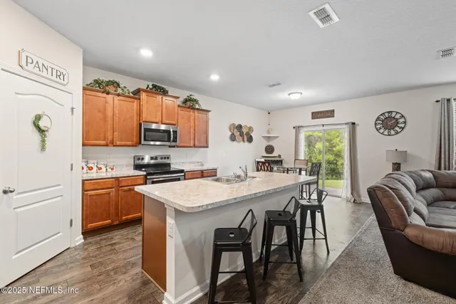 a kitchen with stainless steel appliances granite countertop a stove a refrigerator a kitchen island a table and chairs