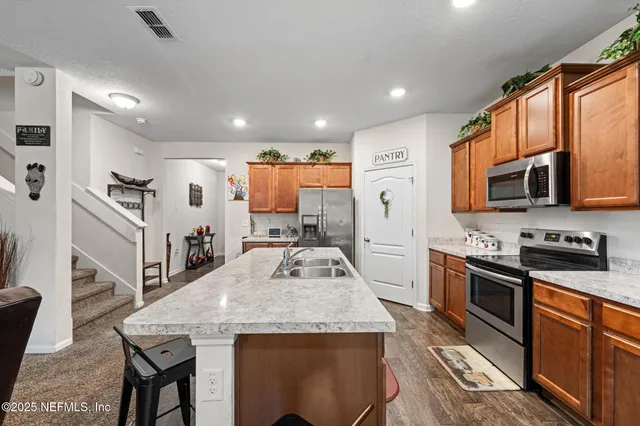 a living room with stainless steel appliances furniture a flat screen tv and a view of kitchen