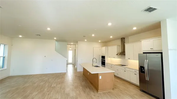 a large white kitchen with a refrigerator a sink and a large window