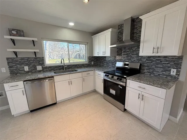 a kitchen with white cabinets appliances a sink and a window