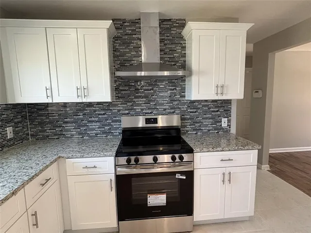 a kitchen with granite countertop white cabinets and stainless steel appliances