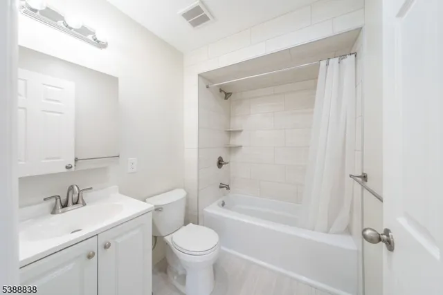 a bathroom with a bathtub shower sink vanity mirror and toilet