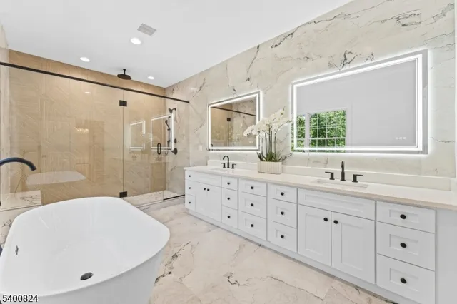 a bathroom with a double vanity sink mirror and bathtub