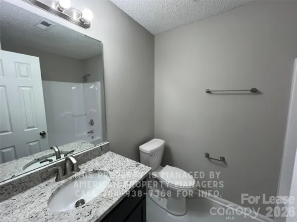 a bathroom with a granite countertop sink a toilet and a mirror