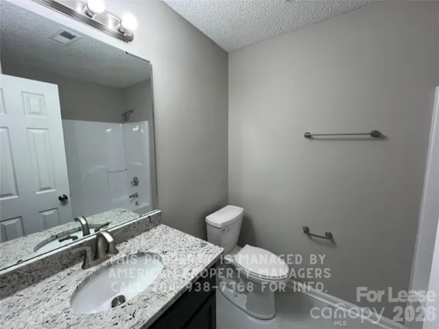 a bathroom with a granite countertop sink a toilet and a mirror