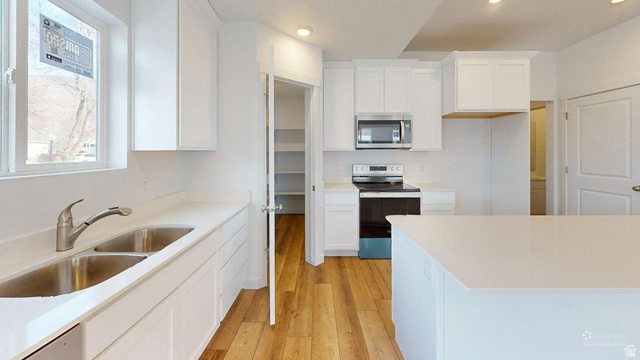 783 Pheasantbrook Drive, Unit 2A Centerville, UT 84014 - Photo 10 of 41 Bright kitchen featuring white cabinetry, light countertops, wood-finish flooring, a stainless steel double sink, and a stainless steel microwave