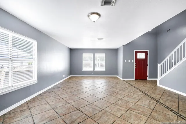 a view of an empty room with window and wooden floor