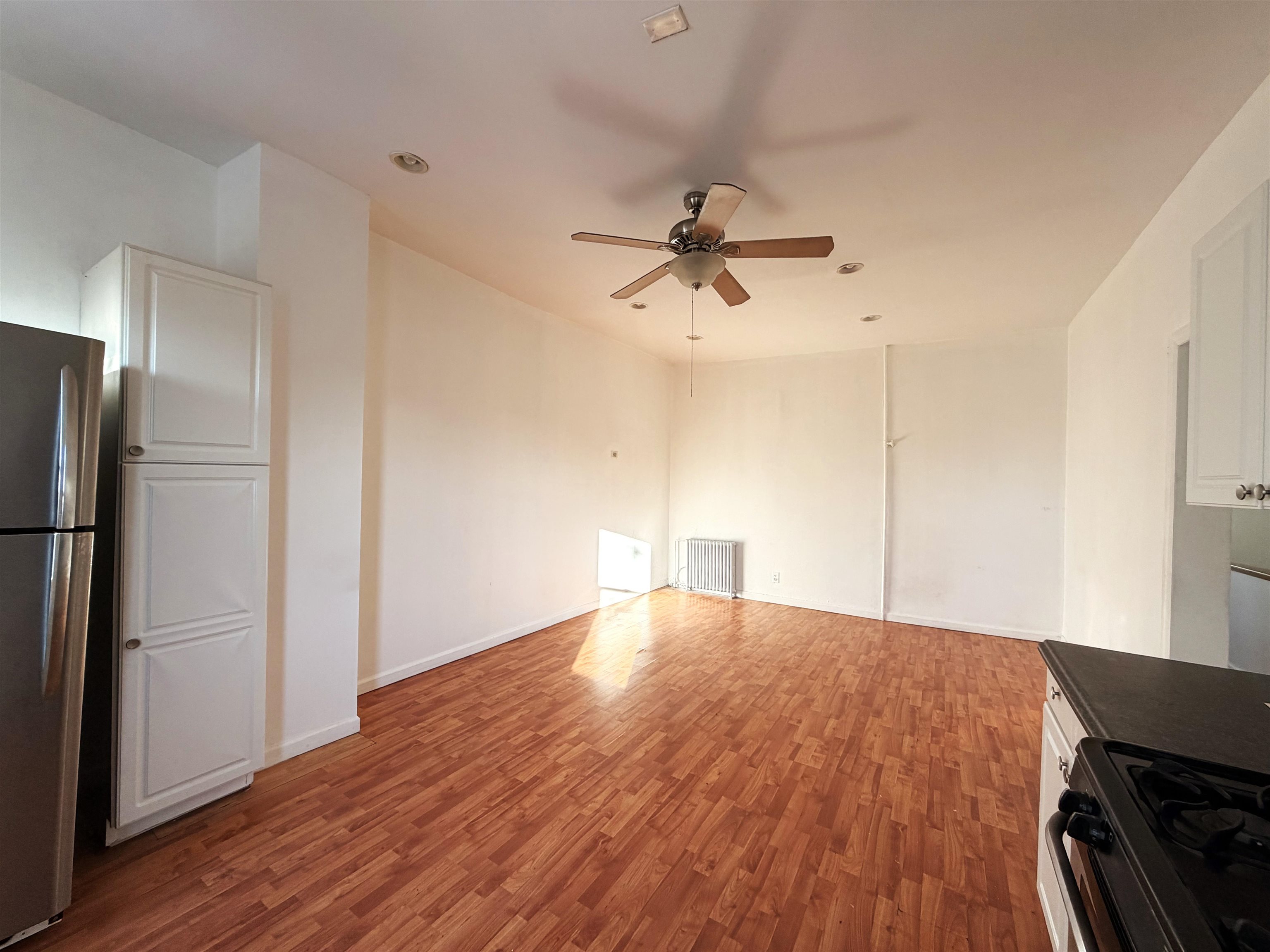 1011 Paterson Plank Road, Unit 2 North Bergen, NJ 07047 - Photo 7 of 12 a view of an empty room with wooden floor and a ceiling fan