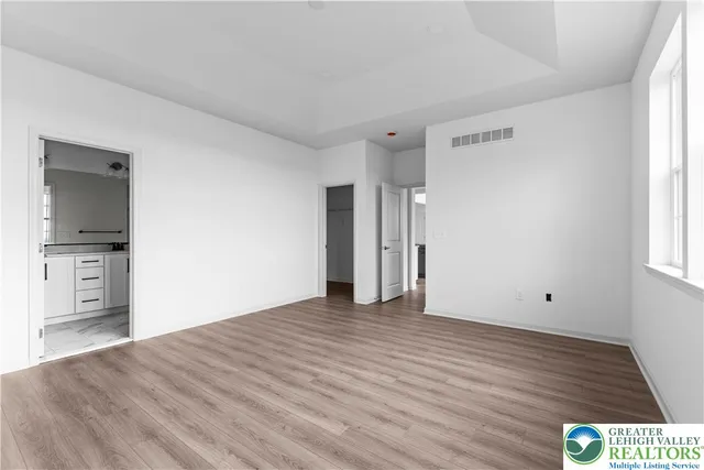 a view of an empty room with window and wooden floor