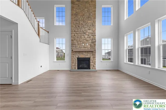 a view of an empty room with wooden floor fireplace and a window