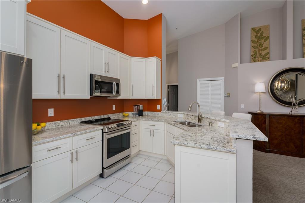 195 Vintage Circle, Unit E205 Naples, FL 34119 - Photo 15 of 34 a kitchen with stainless steel appliances granite countertop a stove a sink and a microwave