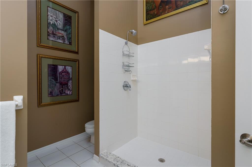 195 Vintage Circle, Unit E205 Naples, FL 34119 - Photo 21 of 34 a bathroom with a shower and a painting on the wall
