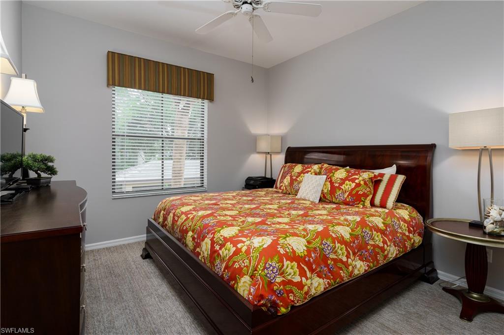 195 Vintage Circle, Unit E205 Naples, FL 34119 - Photo 23 of 34 a large bed sitting in a bedroom next to a lamp next to a window and a lamp