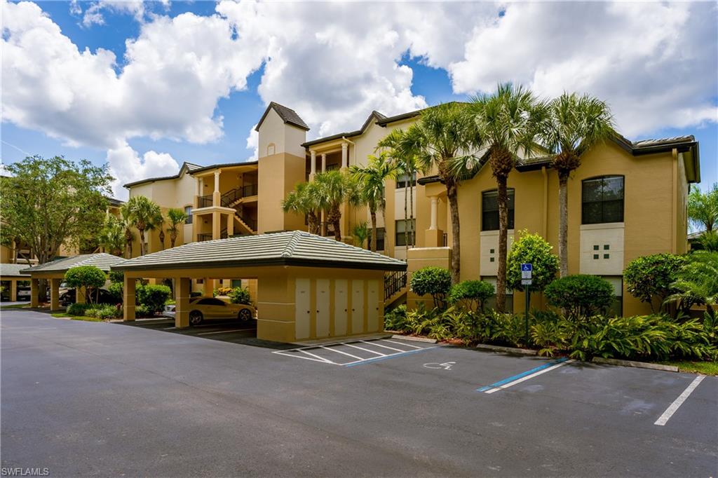 195 Vintage Circle, Unit E205 Naples, FL 34119 - Photo 3 of 34 a view of a white house with a yard and table and chairs under an umbrella