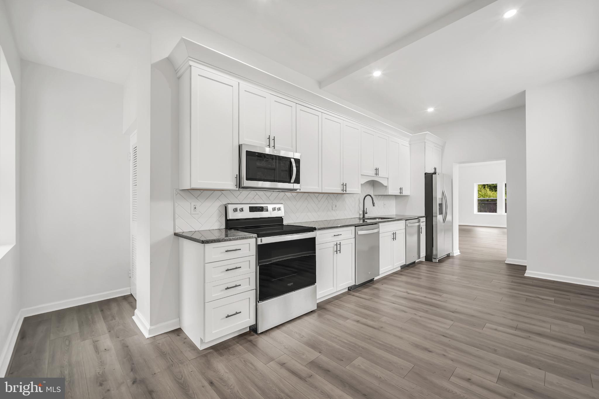 933 Fox Chase Road Jenkintown, PA 19046 - Photo 13 of 39 a kitchen with stainless steel appliances granite countertop a stove top oven a sink and white cabinets with wooden floor