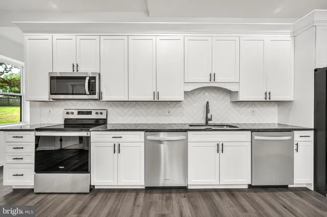 a kitchen with granite countertop white cabinets and stainless steel appliances