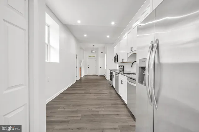 a kitchen with stainless steel appliances granite countertop a refrigerator a stove and a sink with wooden floor