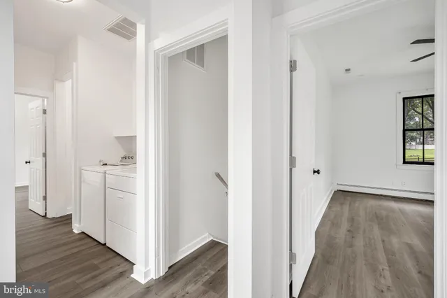 a view of a hallway with empty room and wooden floor