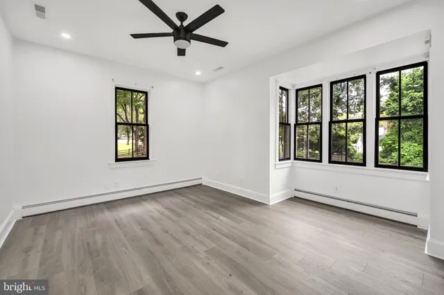 a view of an empty room with a window and wooden floor