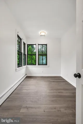 a view of an empty room with a window and wooden floor