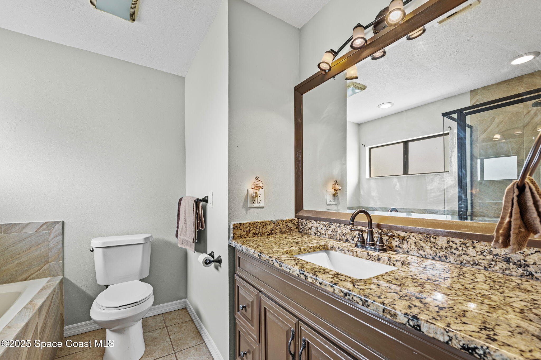 2568 Longwood Boulevard Melbourne, FL 32934 - Photo 20 of 42 a bathroom with a granite countertop sink a toilet and a mirror