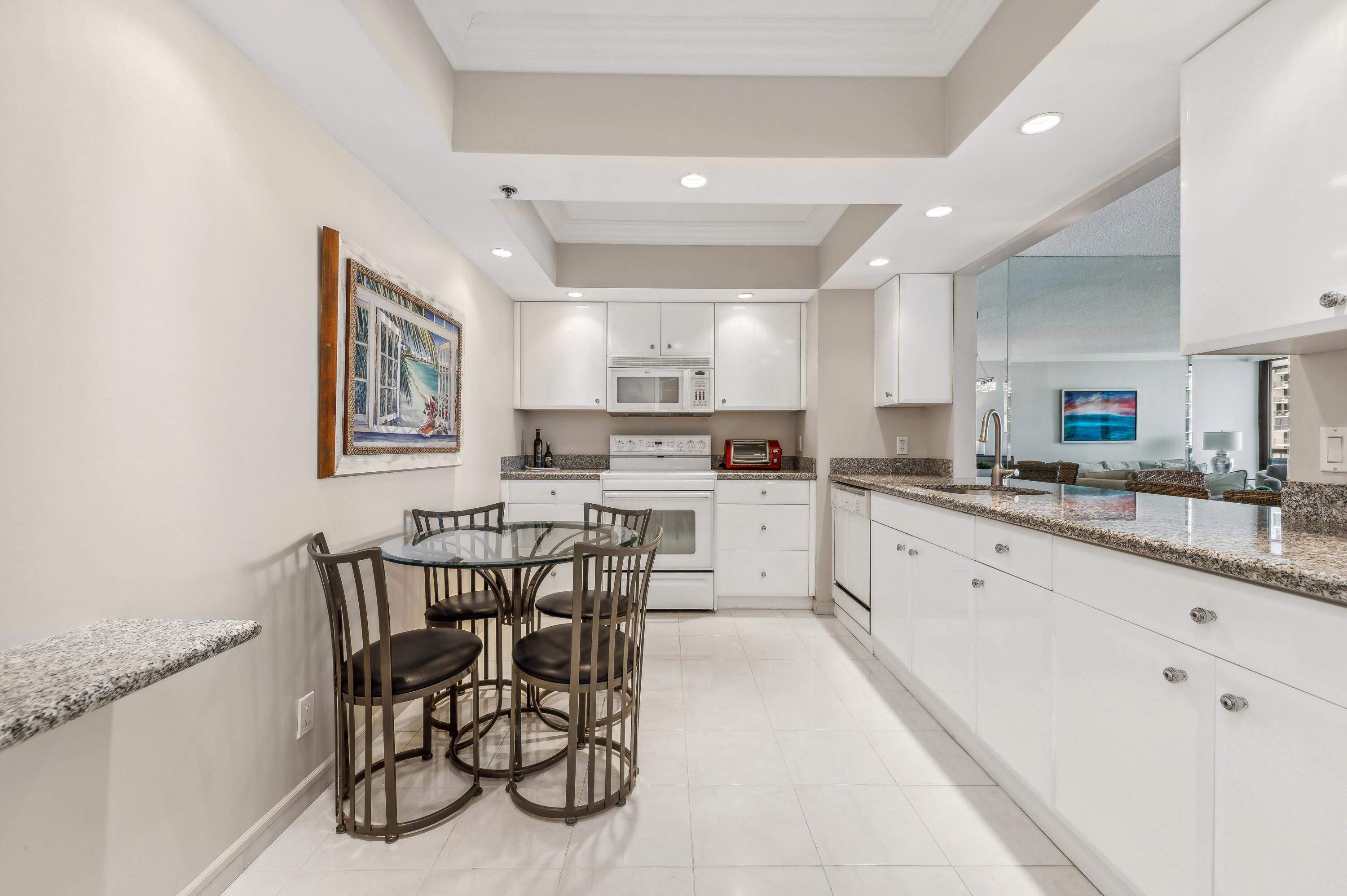 4748 South Ocean Boulevard, Unit 802 Highland Beach, FL 33487 - Photo 9 of 27 a kitchen with granite countertop a table chairs stove and cabinets