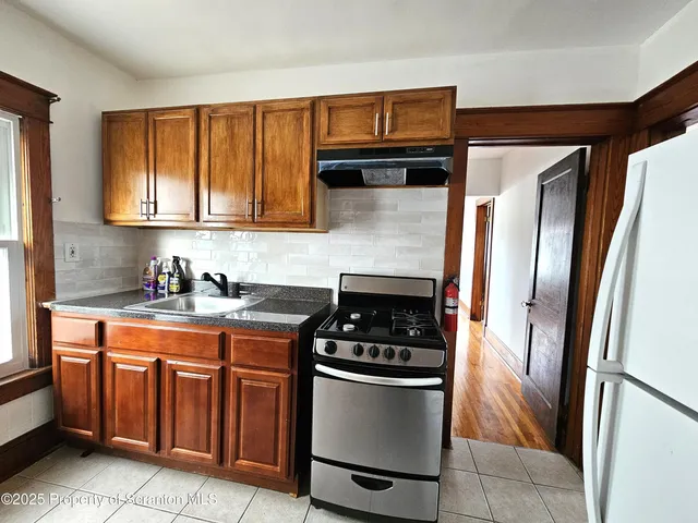 a kitchen with granite countertop a refrigerator stove and sink