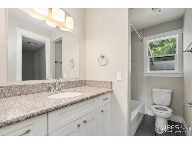 a bathroom with a granite countertop sink toilet a large mirror and a window