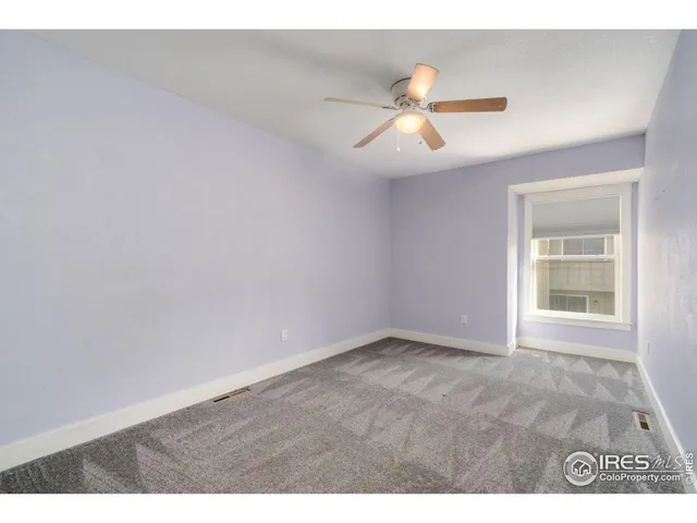 a view of an empty room with wooden floor and window