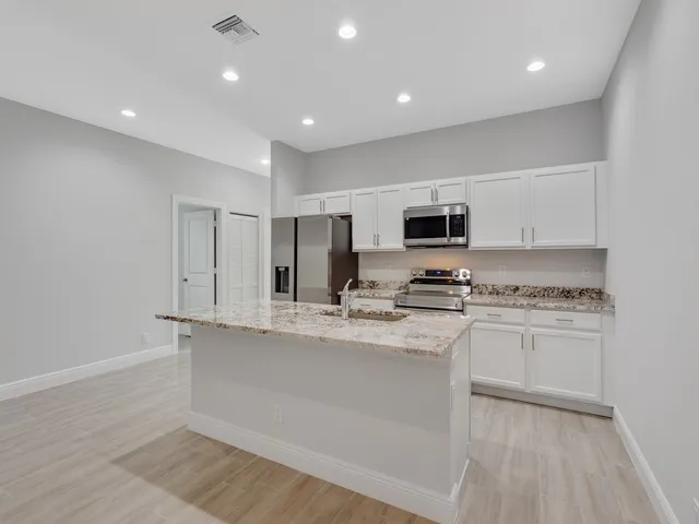 a kitchen with stainless steel appliances granite countertop a stove a sink and a refrigerator