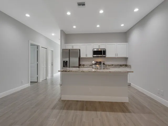 a view of kitchen with stainless steel appliances granite countertop a stove a sink and a refrigerator