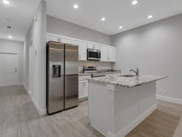 a kitchen with stainless steel appliances granite countertop a refrigerator and a stove top oven
