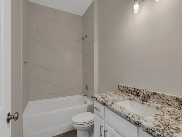 a bathroom with a granite countertop toilet a sink and a bathtub