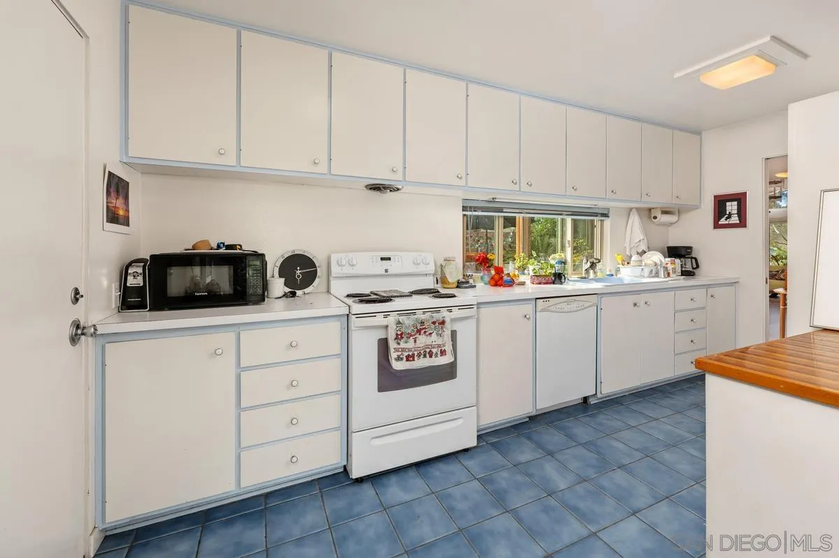 4875 Academy Street San Diego, CA 92109 - Photo 12 of 33 a kitchen with white cabinets and white appliances