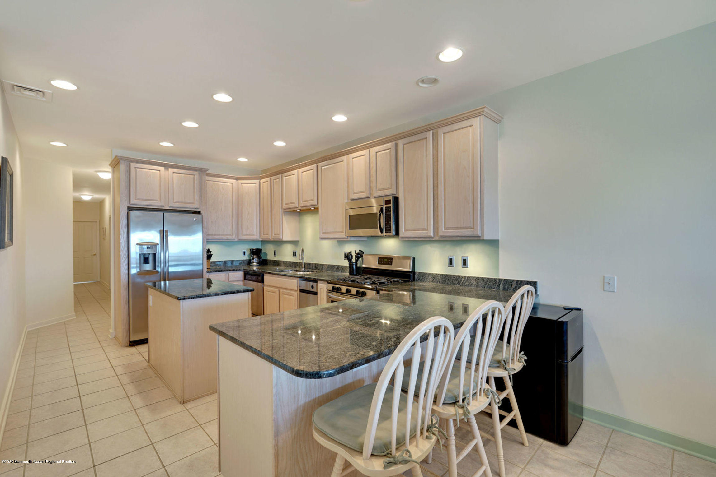 209 Beach Front, Unit 1 Manasquan, NJ 08736 - Photo 11 of 40 a kitchen with a refrigerator a stove a sink and a dining table with wooden floor