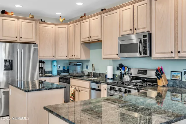 a kitchen with stainless steel appliances granite countertop a sink a stove top oven a counter space and cabinets