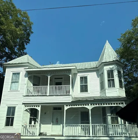 a living room with stainless steel appliances furniture a rug and a refrigerator