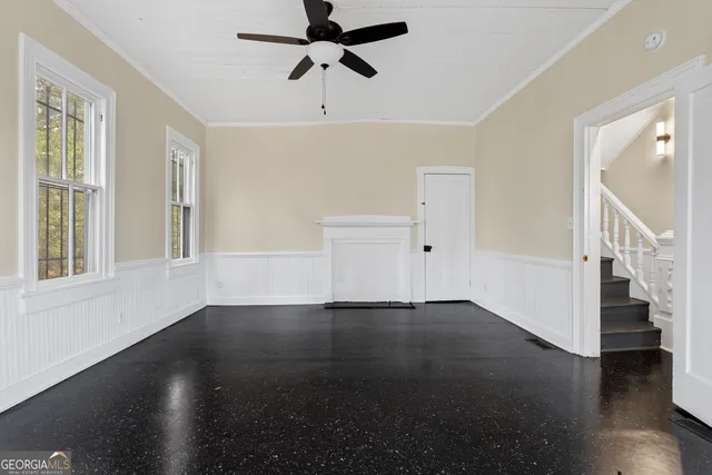an empty room with wooden floor cabinet and windows