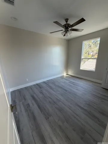 an empty room with wooden floor fan and windows