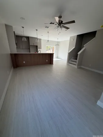 a living room with kitchen view and a wooden floor