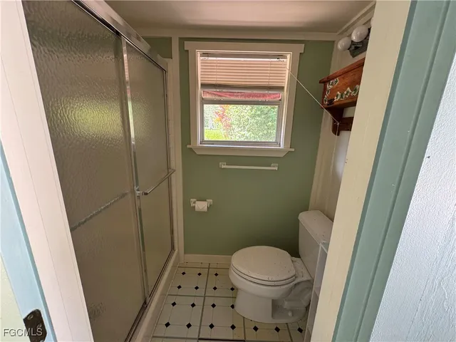 a bathroom with a sink a toilet a window and shower
