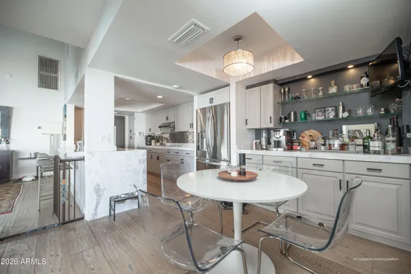 a kitchen with stainless steel appliances kitchen island granite countertop a table chairs and a refrigerator