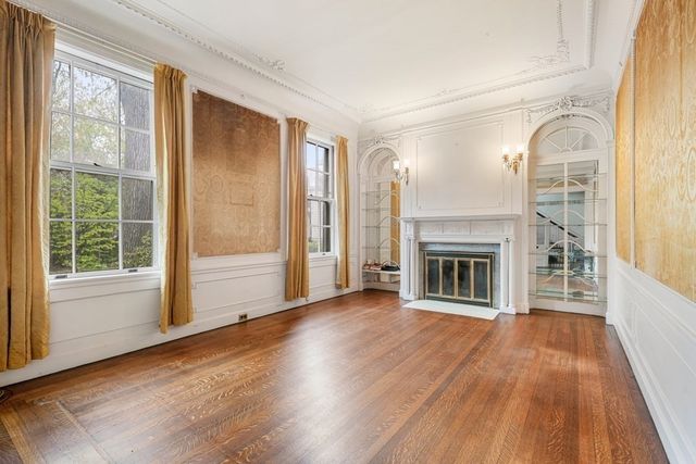 a view of a livingroom with wooden floor a fireplace and windows
