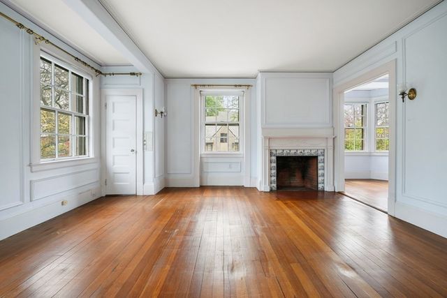 a view of an empty room with window wooden floor and fire place