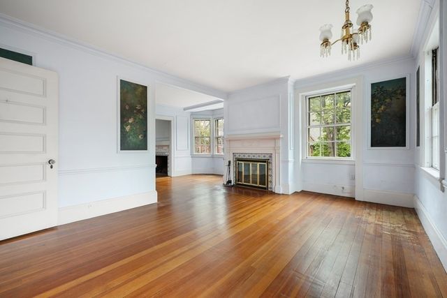 an empty room with wooden floor fireplace and windows