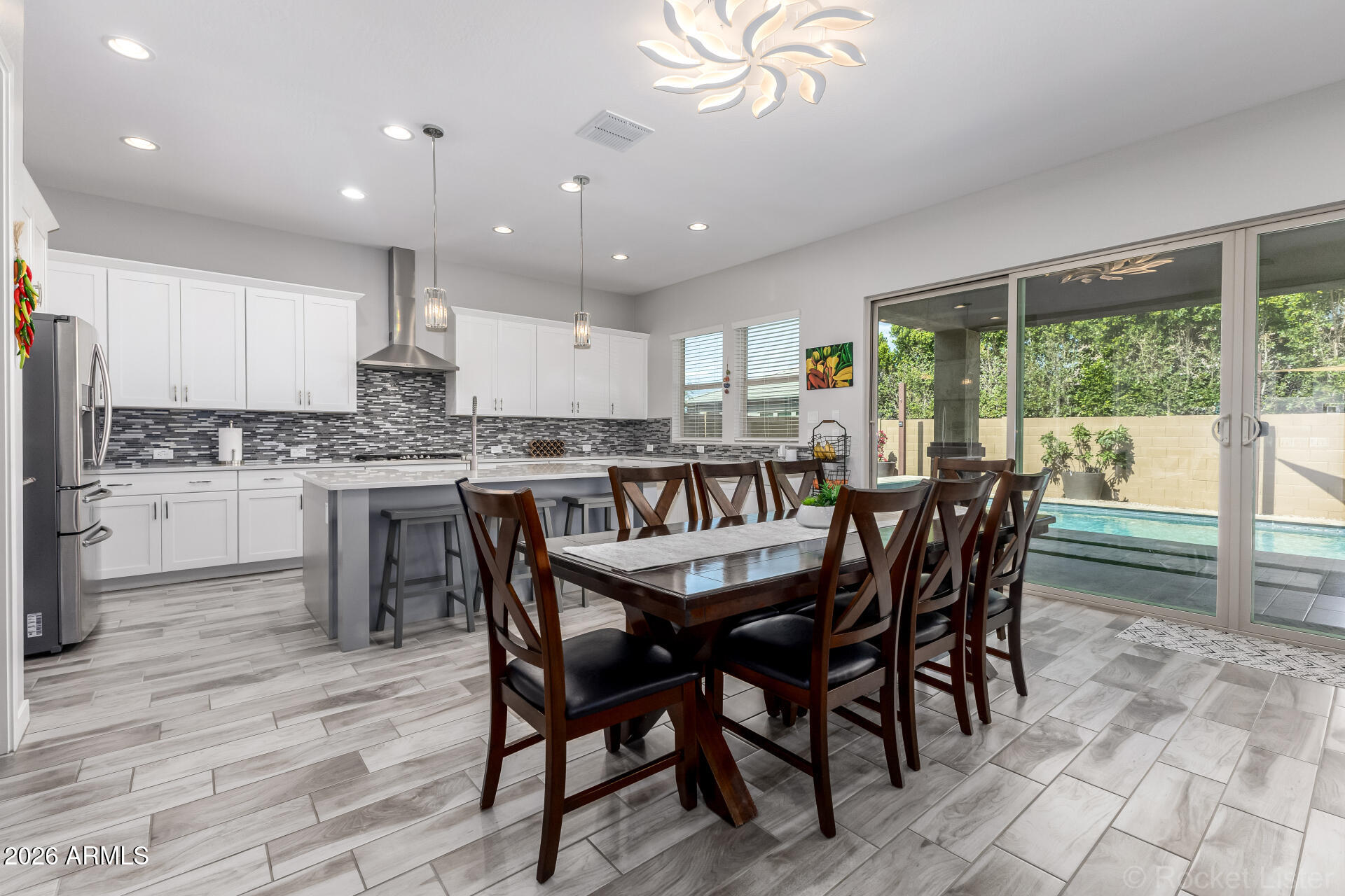 3494 East Spring Wheat Lane Gilbert, AZ 85296 - Photo 3 of 39 a dining room with stainless steel appliances a table chairs and a refrigerator