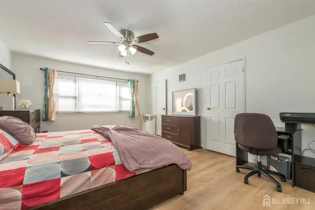 a bedroom with a bed a desk and chair with window